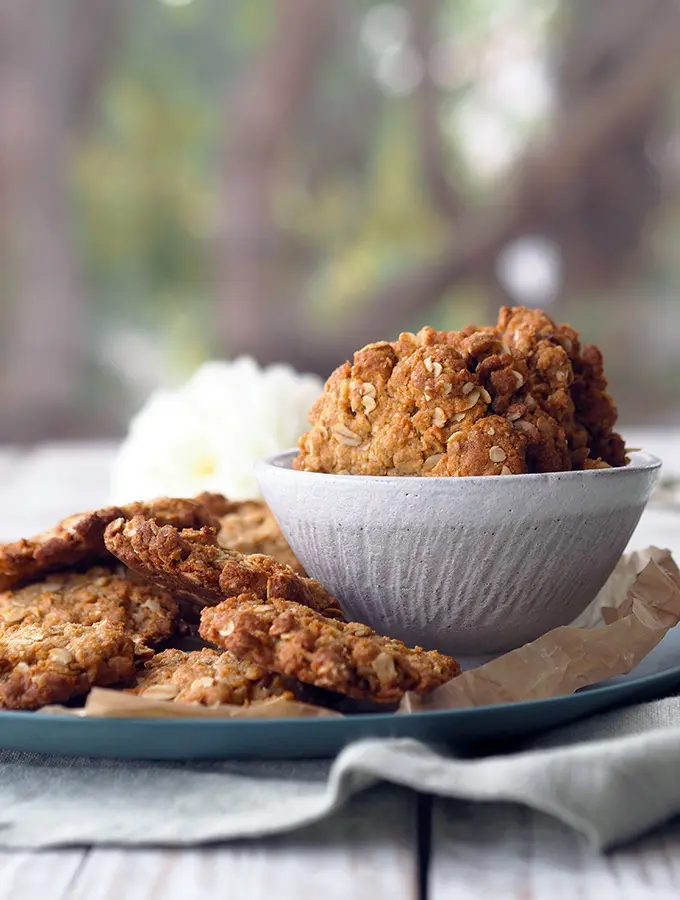 bowl and plate of Anzac biscuits sitting on a table in front of a window