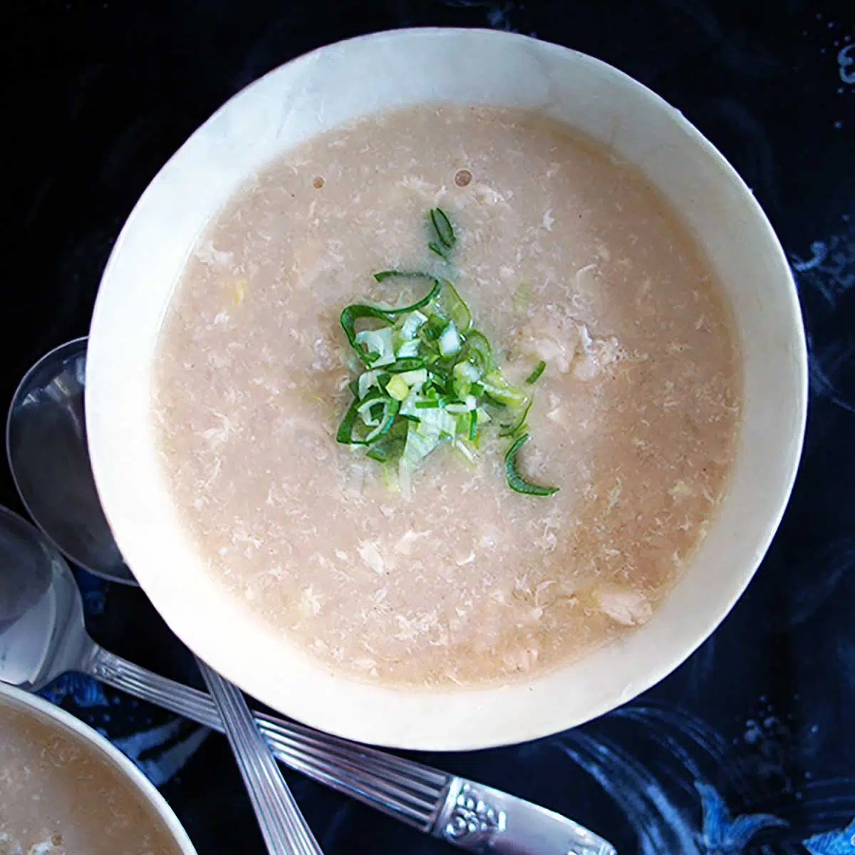 a bowl of chicken and rice soup garnished with spring onions