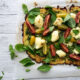 zucchini pizza base recipe with fresh heirloom tomatoes, basil, pesto and mozzarella cheese