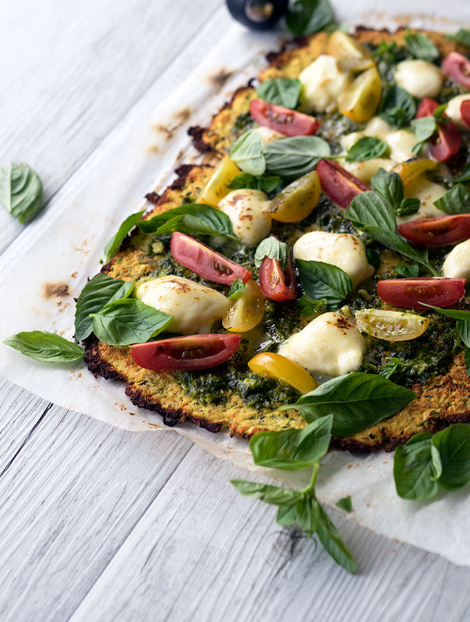 zucchini pizza base recipe with fresh heirloom tomatoes, basil, pesto and mozzarella cheese