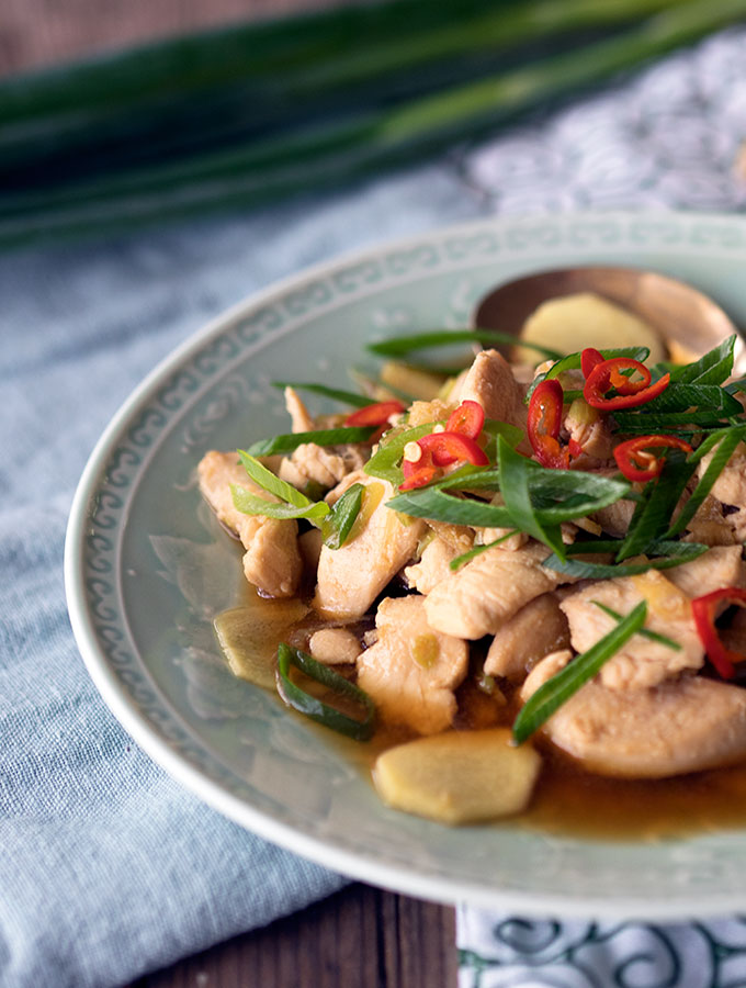 dish on a green plate garnished with slices of shallot and chilli