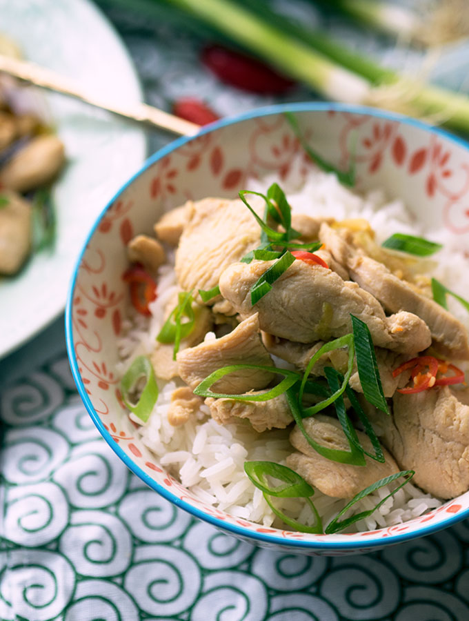 Drunken Chicken sitting on steamed rice in a red and white bowl