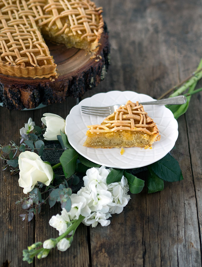 pineapple tart sitting on a round wooden board with a slice removed, slice on white plate in the foreground