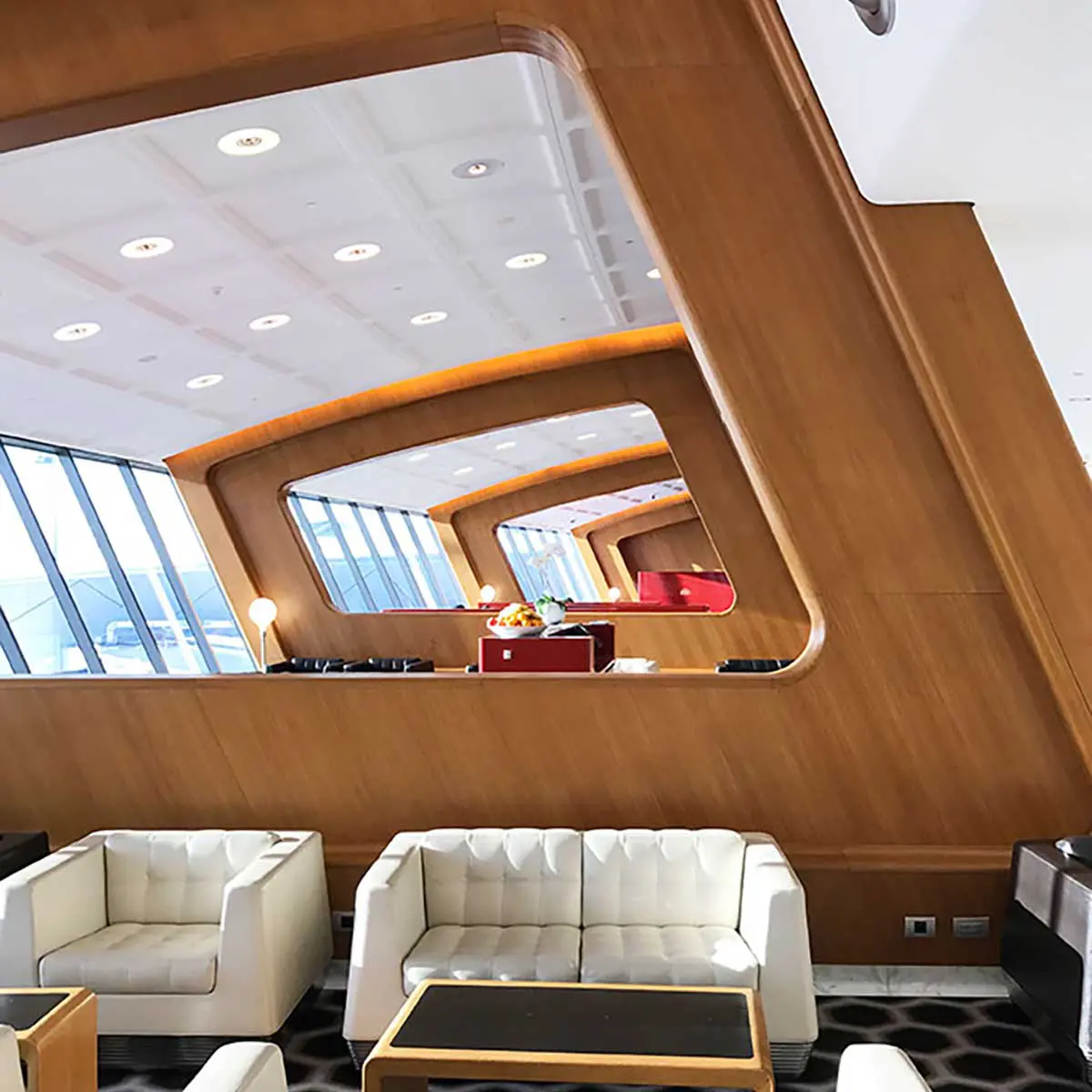 one of the seating areas of the qantas first class lounge in Sydney with cream sofas and wooden artistic walls