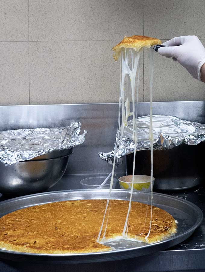 Cheese being stretched from from fresh Kanafeh