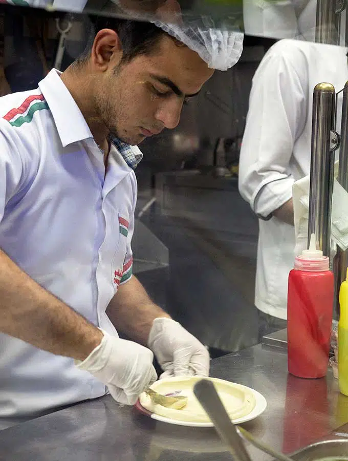 Hummus being plated by a chef