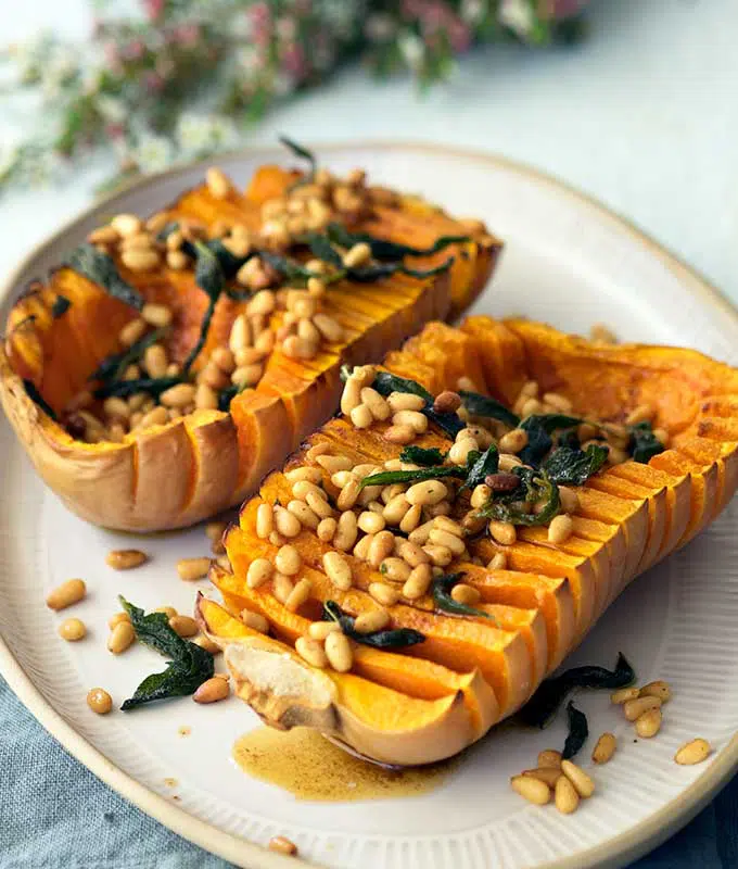 Hasselback pumpkin with browned butter pine nuts and sage on a serving plate