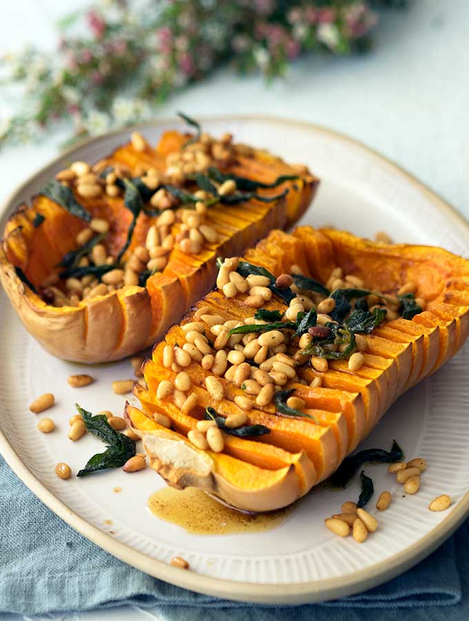 Hasselback pumpkin with browned butter pine nuts and sage on a serving plate