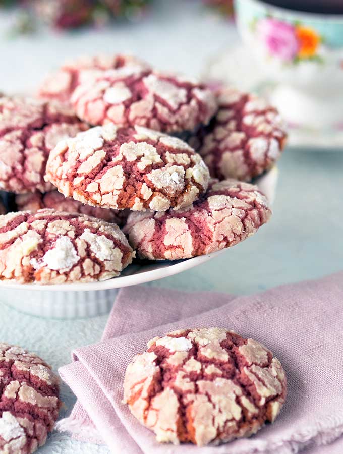 Ruby Chocolate Crackle Cookies on a raised plate with extra on the table