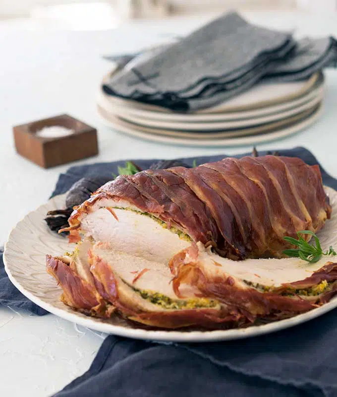 Whole prosciutto wrapped turkey breast with tarragon citrus butter sliced on the table
