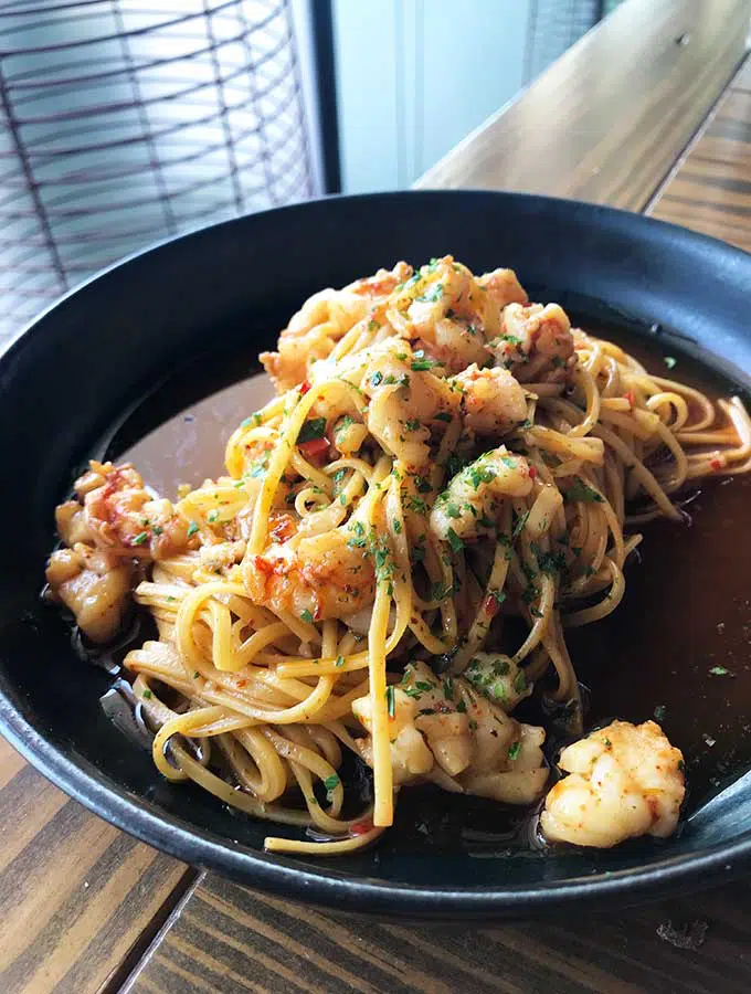 black plate with spaghetti with prawns and cream sauce