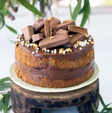 coffee sponge filled with tim tam spread on a wooden cake stand decorated with tim tams