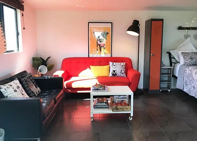 lounge room with red sofa, dog print on wall, white table, stand light and cupboard at the dog house port macquarie