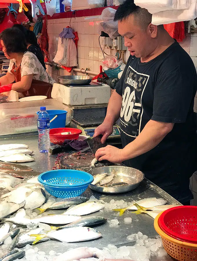 fishmonger preparing fish for his patrons at the red market macao