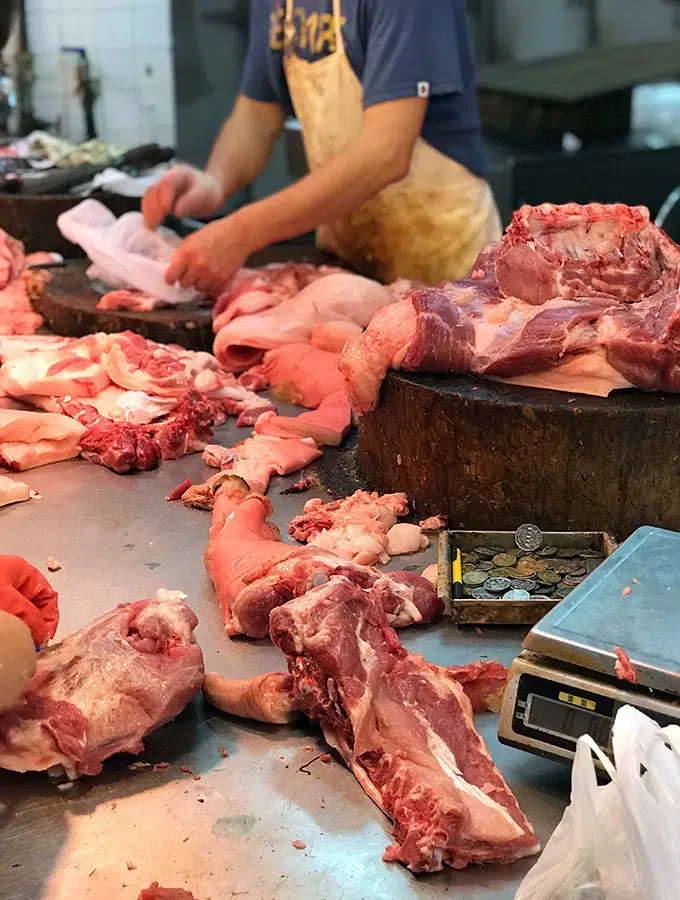 butcher cutting up pieces of pork at the red market macao