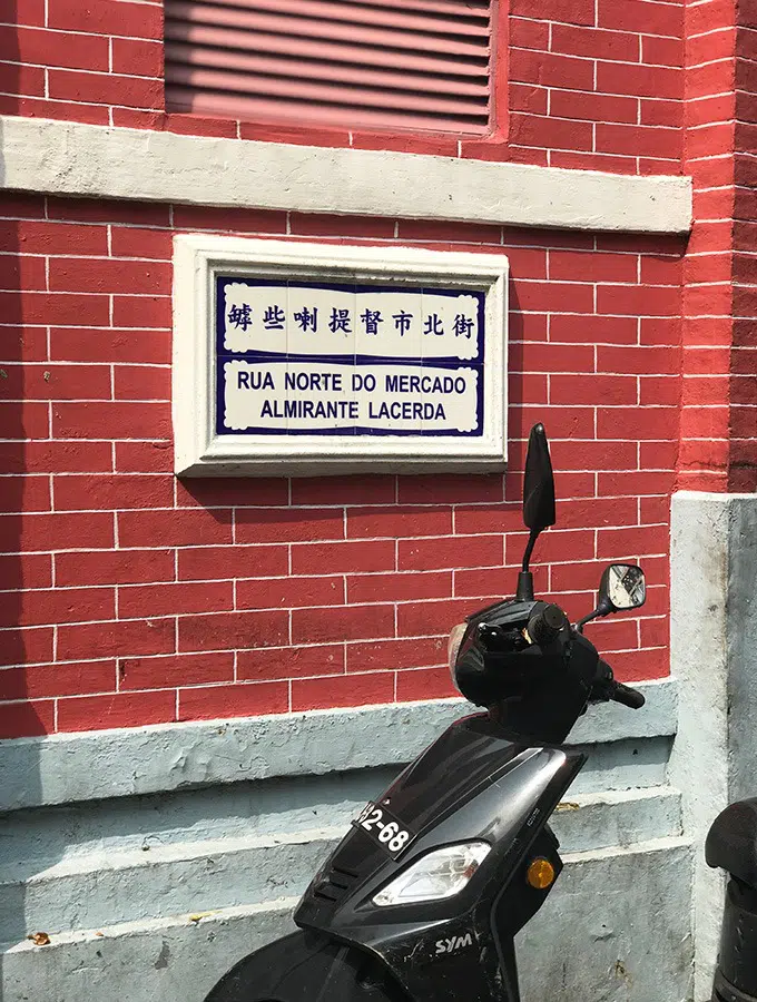 street sign on the red bricks of the red market macao with scooter in front