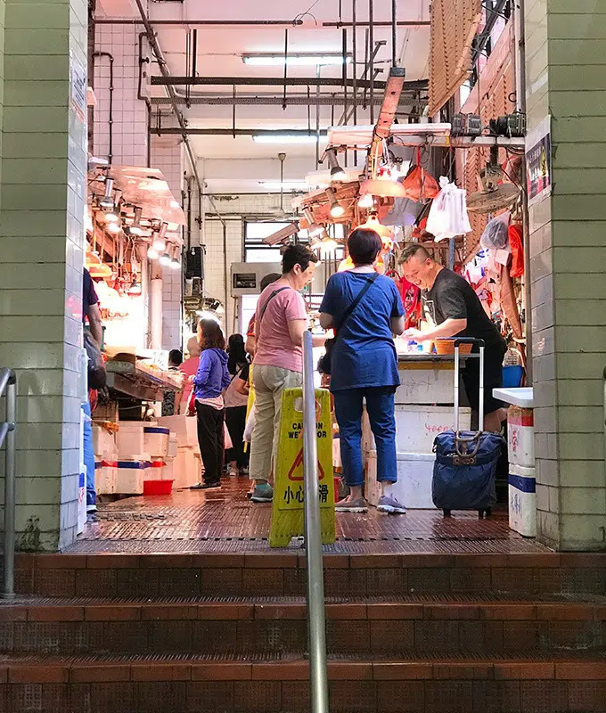people standing at the top of a staircase looking at seafood to purchase at the red market macao