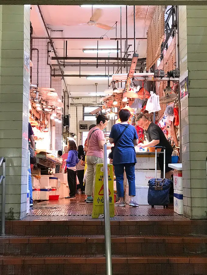 people standing at the top of the stairs looking at seafood to purchase at the red market macao