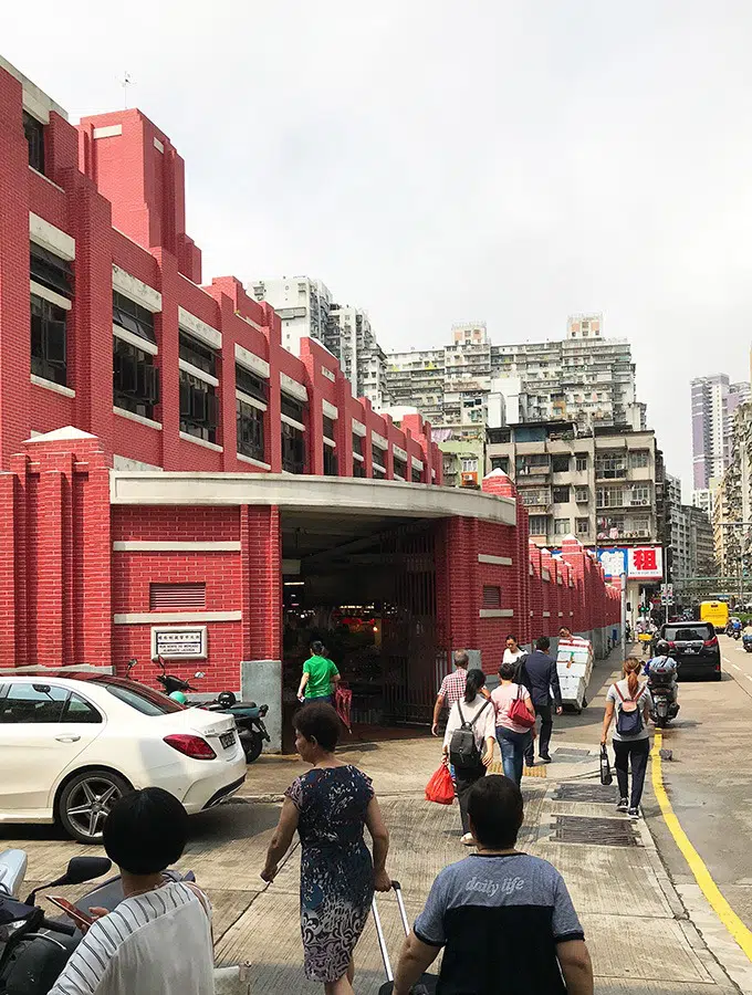 the outside of the red market building in macao with people walking