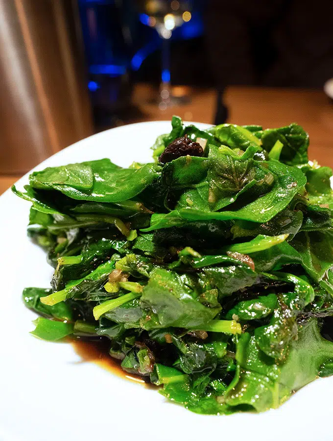 stir fried warrigal greens on a white plate