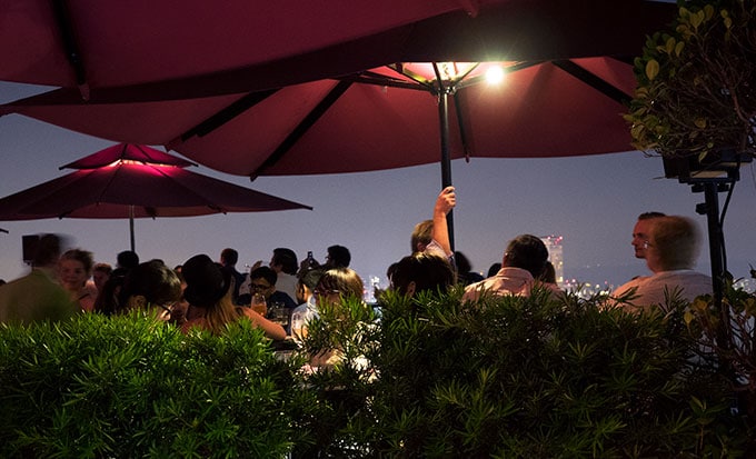 tables, chairs, people and red umbrellas at night - Ce La Vi Singapore