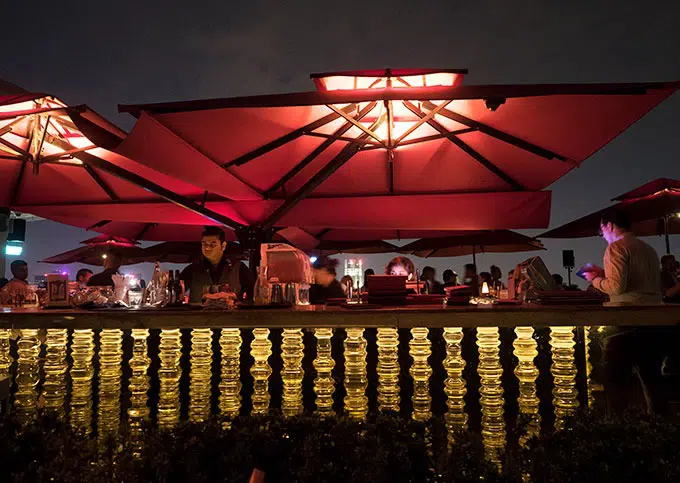 bar with a big red umbrella over the top at night - Ce La Vi Singapore