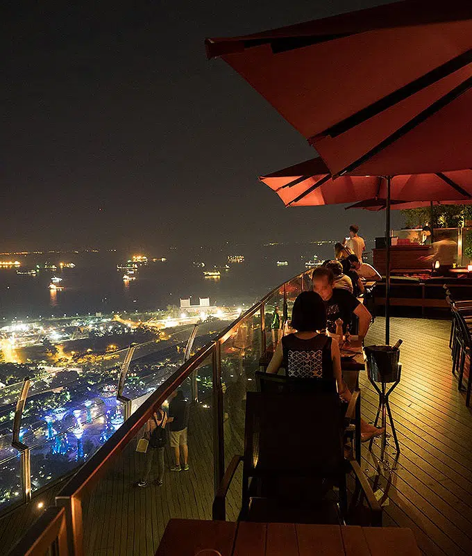 tables and umbrellas on the 57th floor of marina bay sands looking out on the view of singapore at night Ce La Vi Singapore