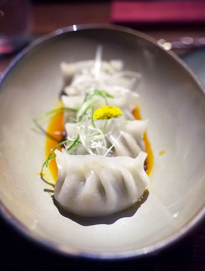 dumplings on a plate with sauce - Ce La Vi Singapore