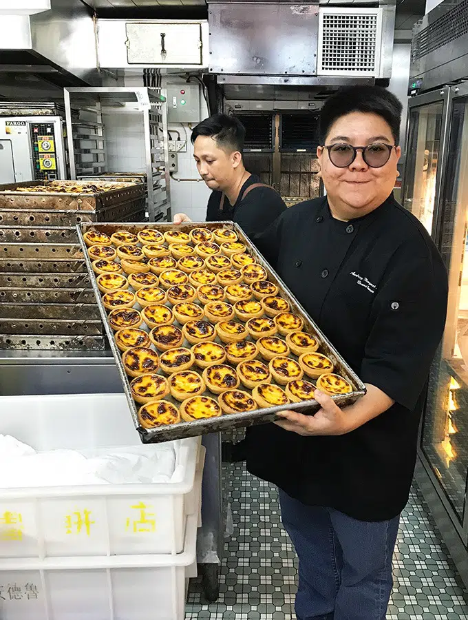 audrey stow holding a tray of macanese egg tarts in her bakery