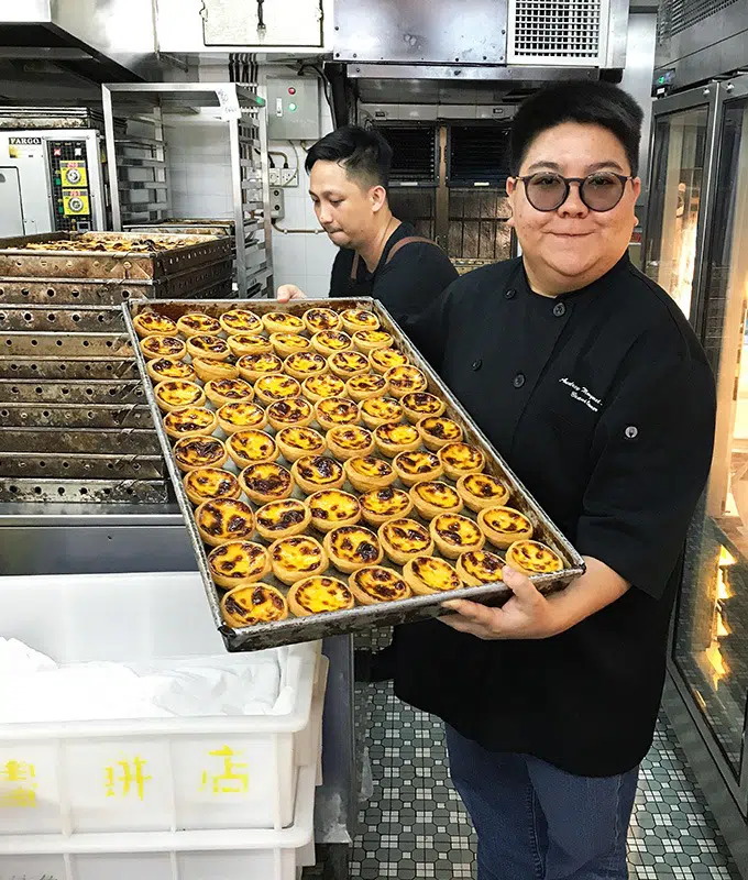 audrey stow holding a tray of macanese egg tarts in her bakery