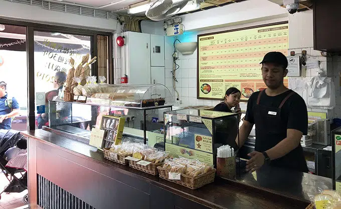 two staff members at the bakery counter serving partrons