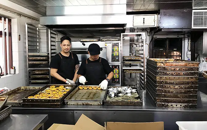 2 bakers in the bakery kitchen making egg tarts