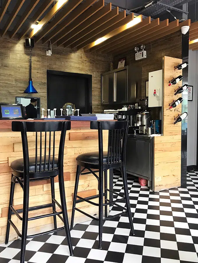 two black bar seats at a wooden bar in the cafe