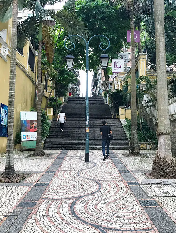 tiled street in Macao leading up to a set of stairs with palm trees either side