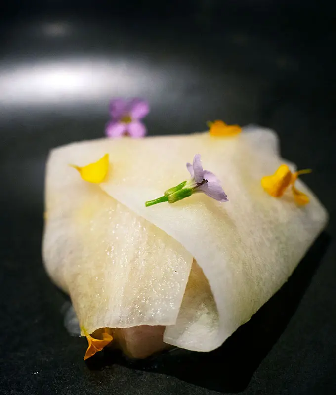 a parcel of mackrel inside ribbons of daikon with flowers on top at bangalay dining