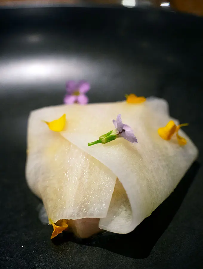 a parcel of mackrel inside ribbons of daikon with flowers on top at bangalay dining