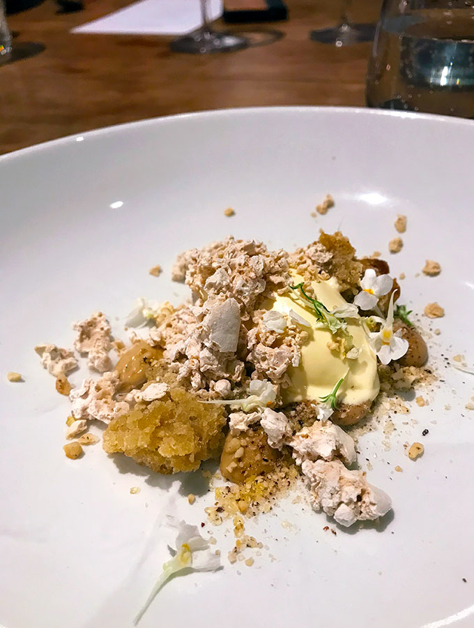 wattleseed ice cream with macadamia and caramelised white chocolate on a plate with edible flowers at bangalay dining