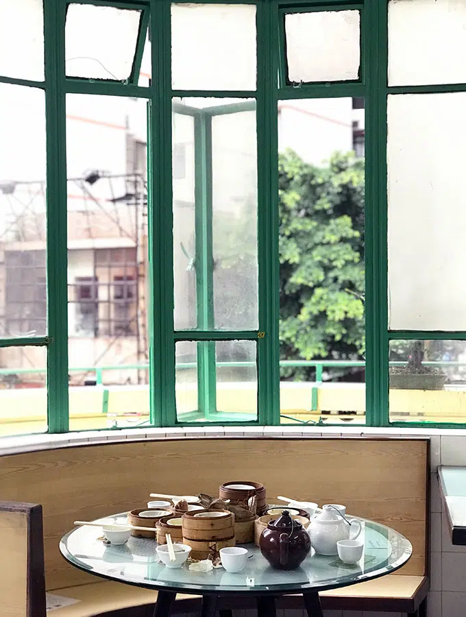 table after diners have left in front of a green framed windows