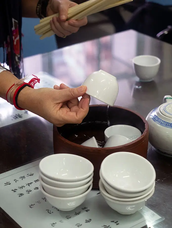 a person washing small white tea cups before serving tea