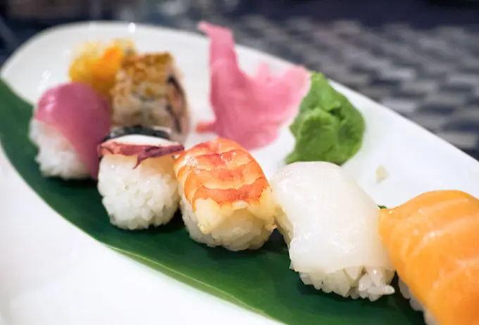 various sushi on a plate with ginger and wasabi