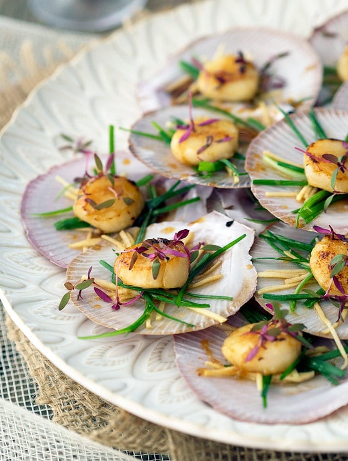 seared scallops with sake butter sauce on a large white plate