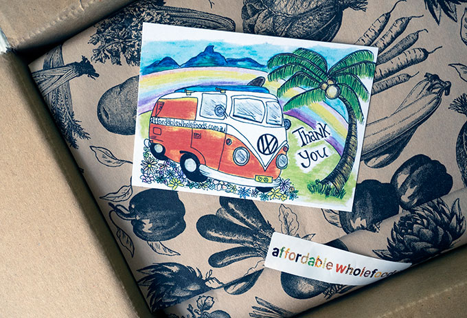 wholefood items wrapped up in paper in a box with a postcard