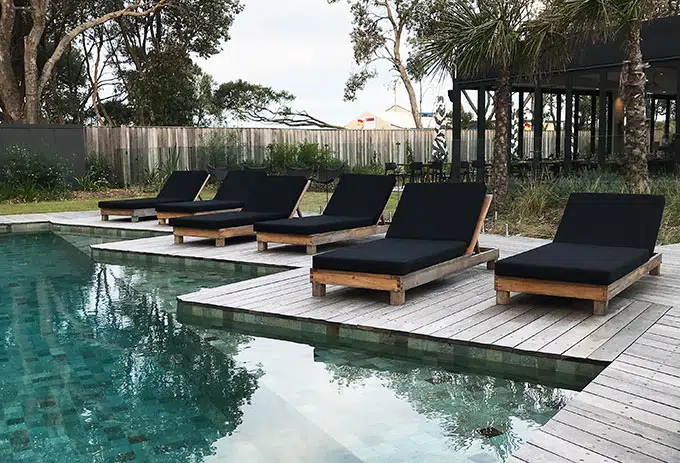 pool lounge recliner chairs with black cushions next to the pool