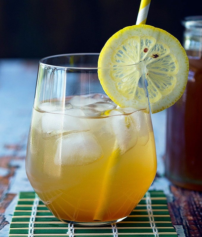 glass containing cola soda with a slice of lemon on the rim and a straw