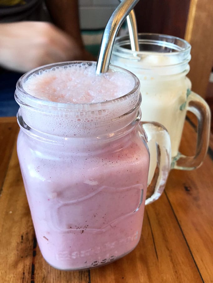 two mason jars containing milkshakes with metal straws