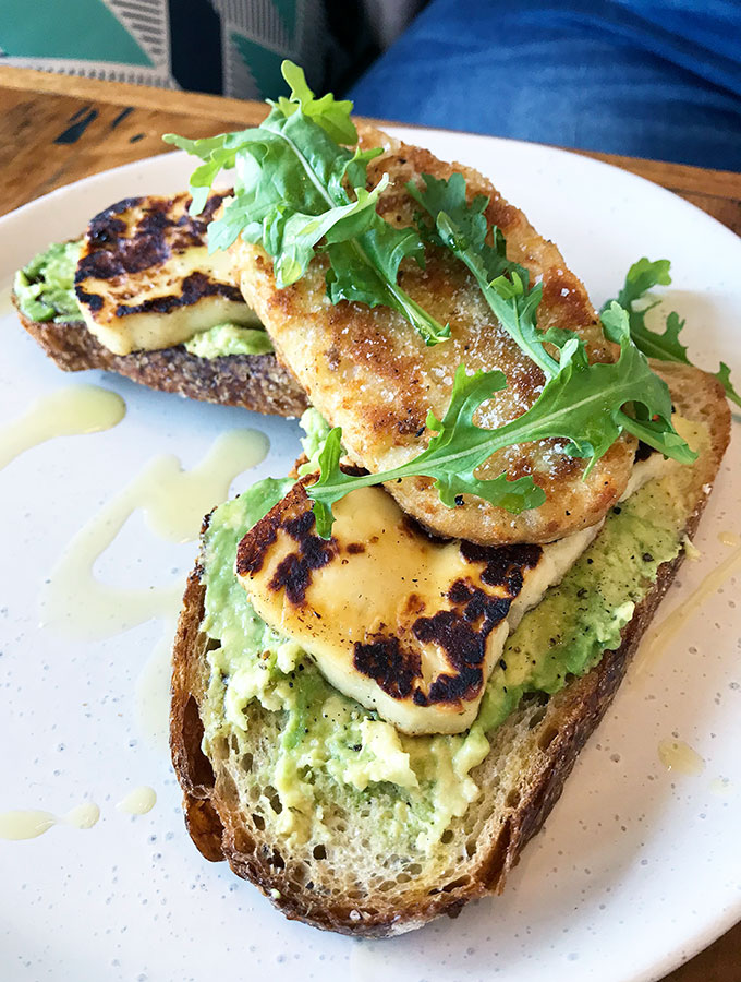 avocado on toast with haloumi and a hash brown on top