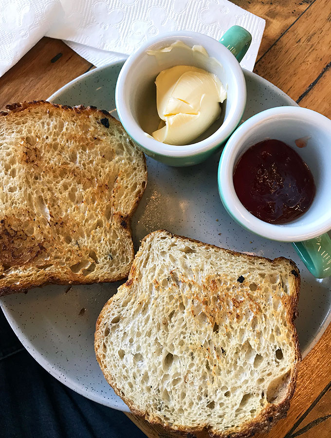 two slices of toast with butter and cream on the side