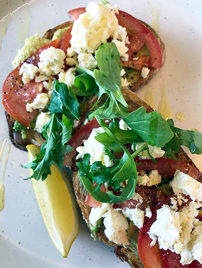 toasted sourdough with tomato and feta. A slice of lemon on the side and parsley on top.