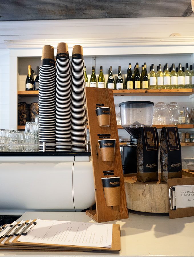 coffee making machine on the bar with various take away cups and bags of coffee