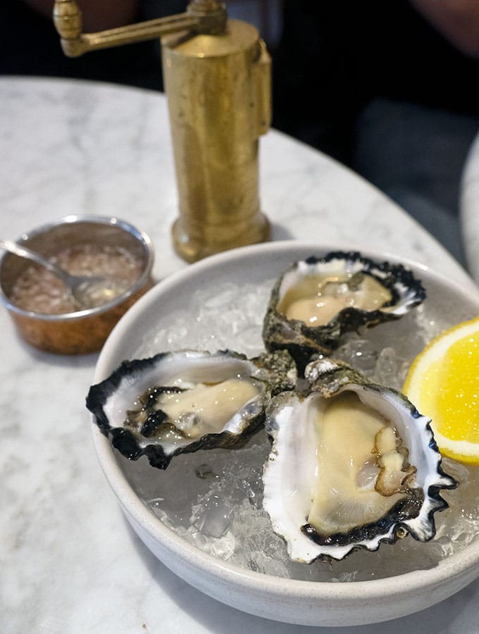 fresh oysters in the shell on a bowl of ice with a slice of lemon